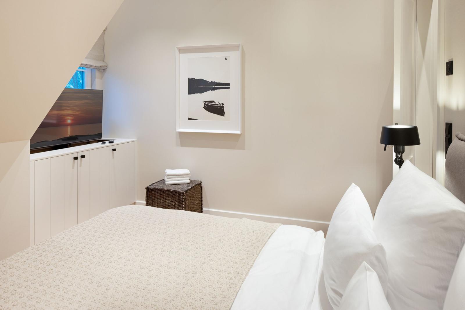 Schlafzimmer mit Bett, Fernseher und Wandbild