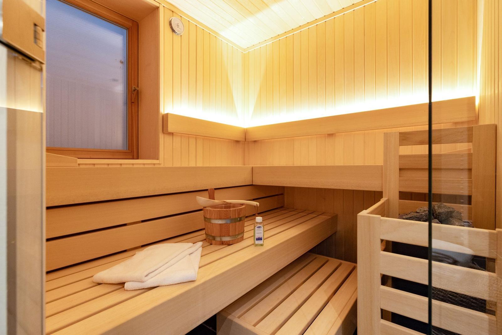 Sauna mit Holzbänken, Eimer, Flasche und Fenster