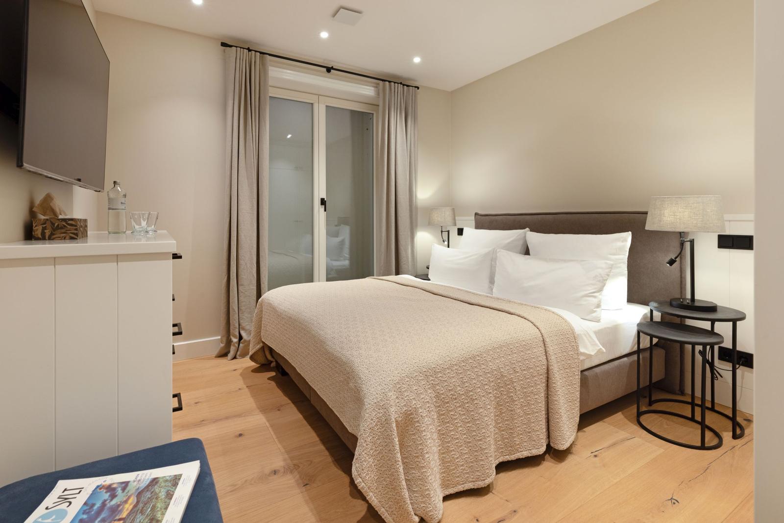 Schlafzimmer mit Doppelbett, TV, Schrank und Terrassentür.