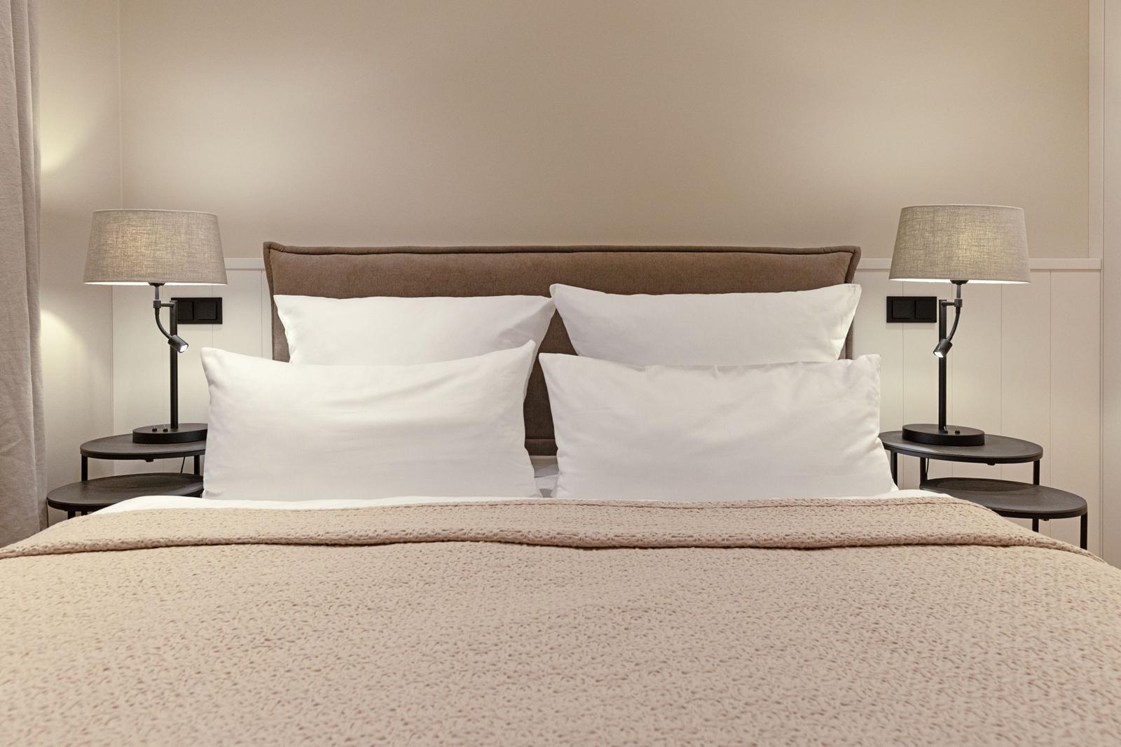 Ein Bett mit vier Kissen und zwei Nachttischen mit Lampen.