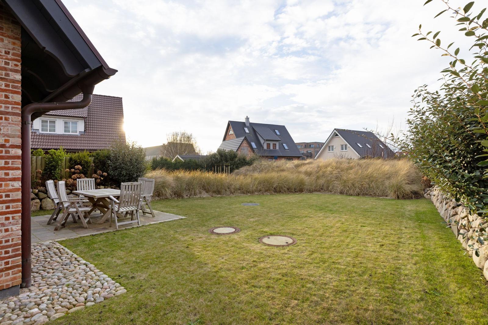 Hinterhof mit Garten, Sitzgelegenheit und Blick auf Nachbarhäuser.