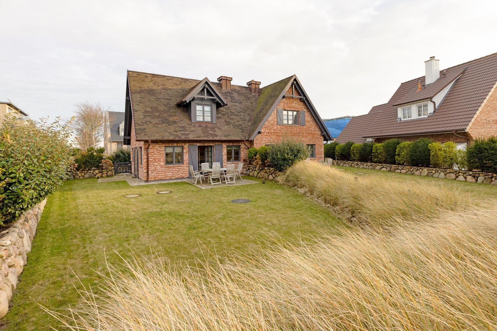 Haus mit Garten und Terrasse mit Sitzgelegenheit.