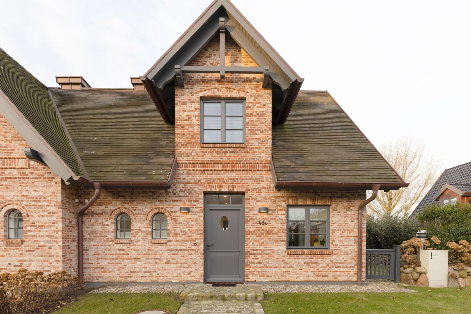 Ein zweistöckiges Haus mit Backsteinfassade und grauer Tür.