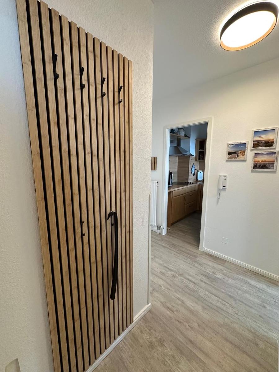 Eingangsbereich mit Holzgarderobe und Blick in die Küche.