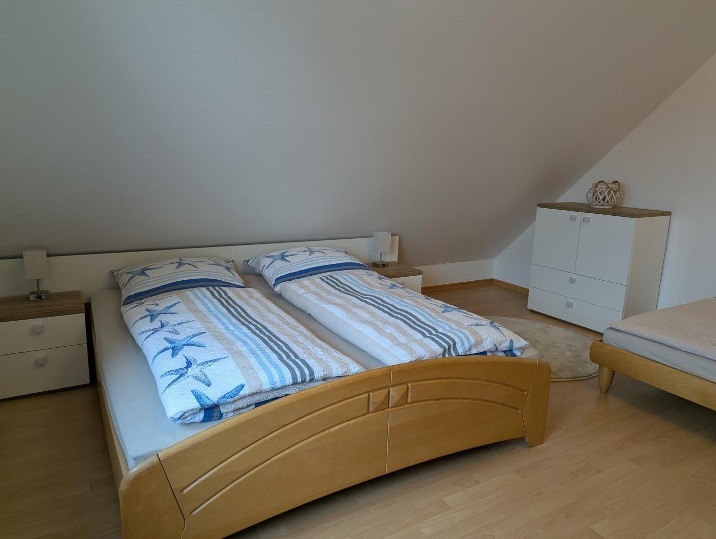 Schlafzimmer mit Doppelbett, Nachttischen und Kleiderschrank unter Dachschrägen.