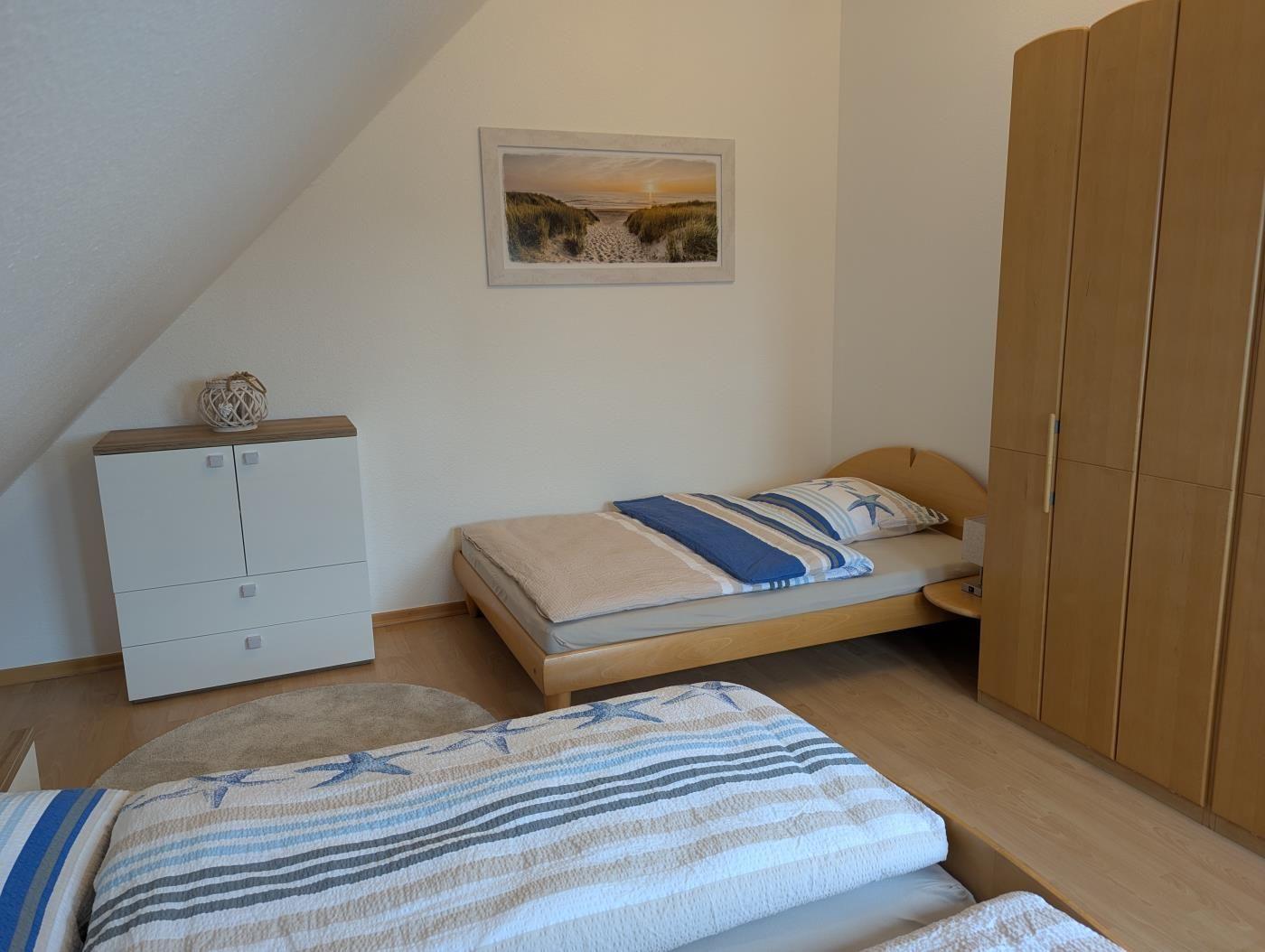Zimmer mit zwei Betten, Kleiderschrank und Bild an der Wand.