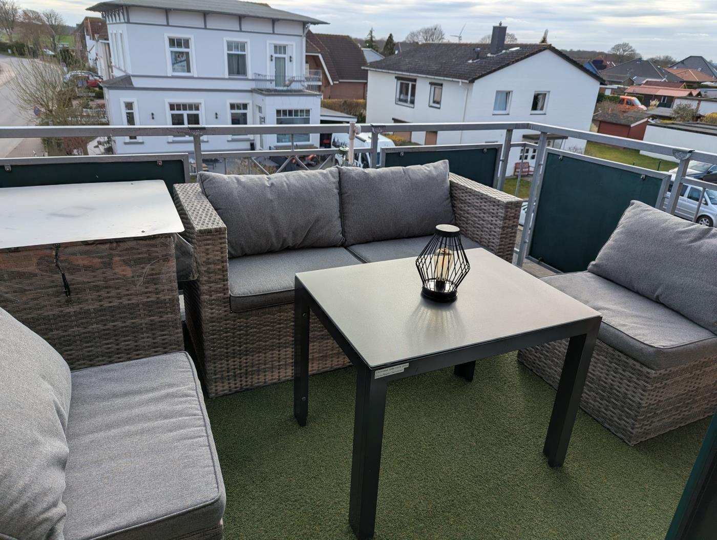 Terrasse mit Gartenmöbeln, Tisch und Blick auf Wohnhäuser.