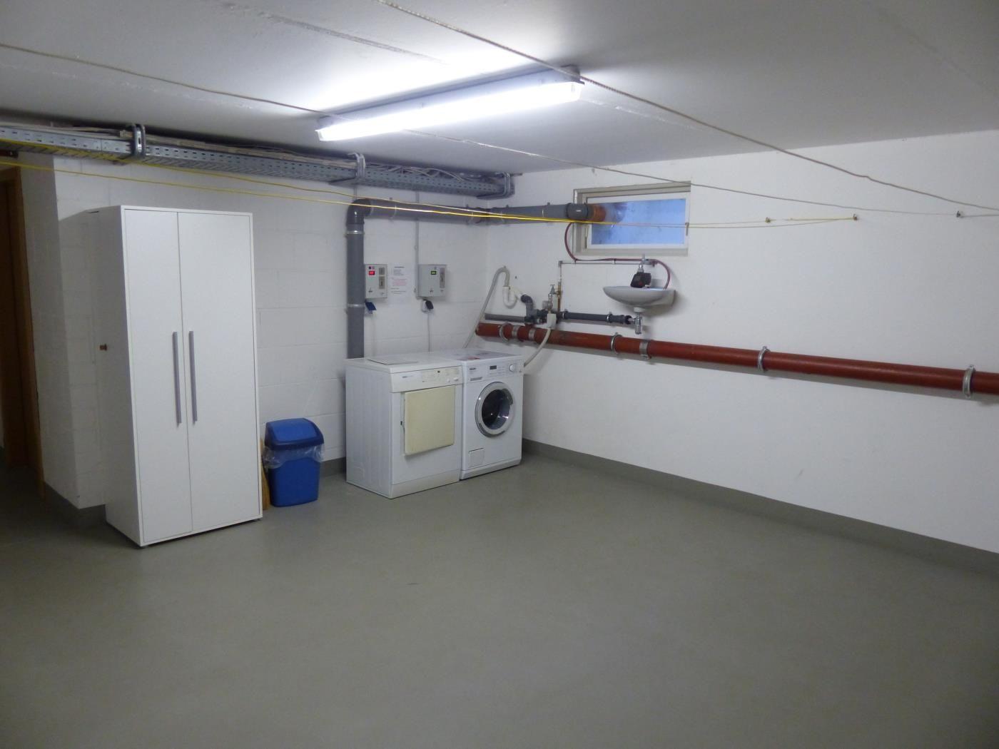Waschraum mit Waschmaschine, Trockner, Spülung und Schrank.
