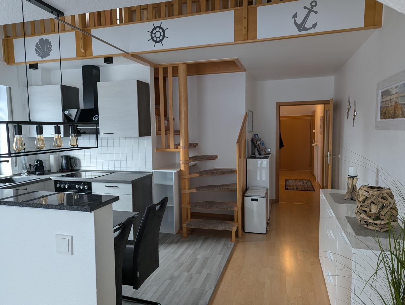 Küche mit Essbereich, Holztreppe und maritimen Dekorationen.