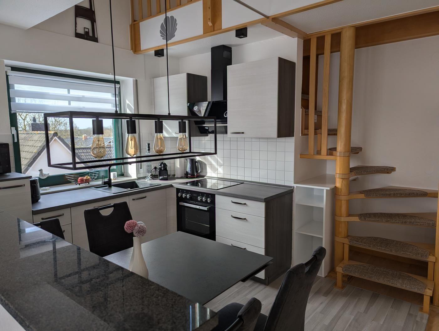Küche mit Essbereich, Holztreppe und Fensterblick auf Dächer.