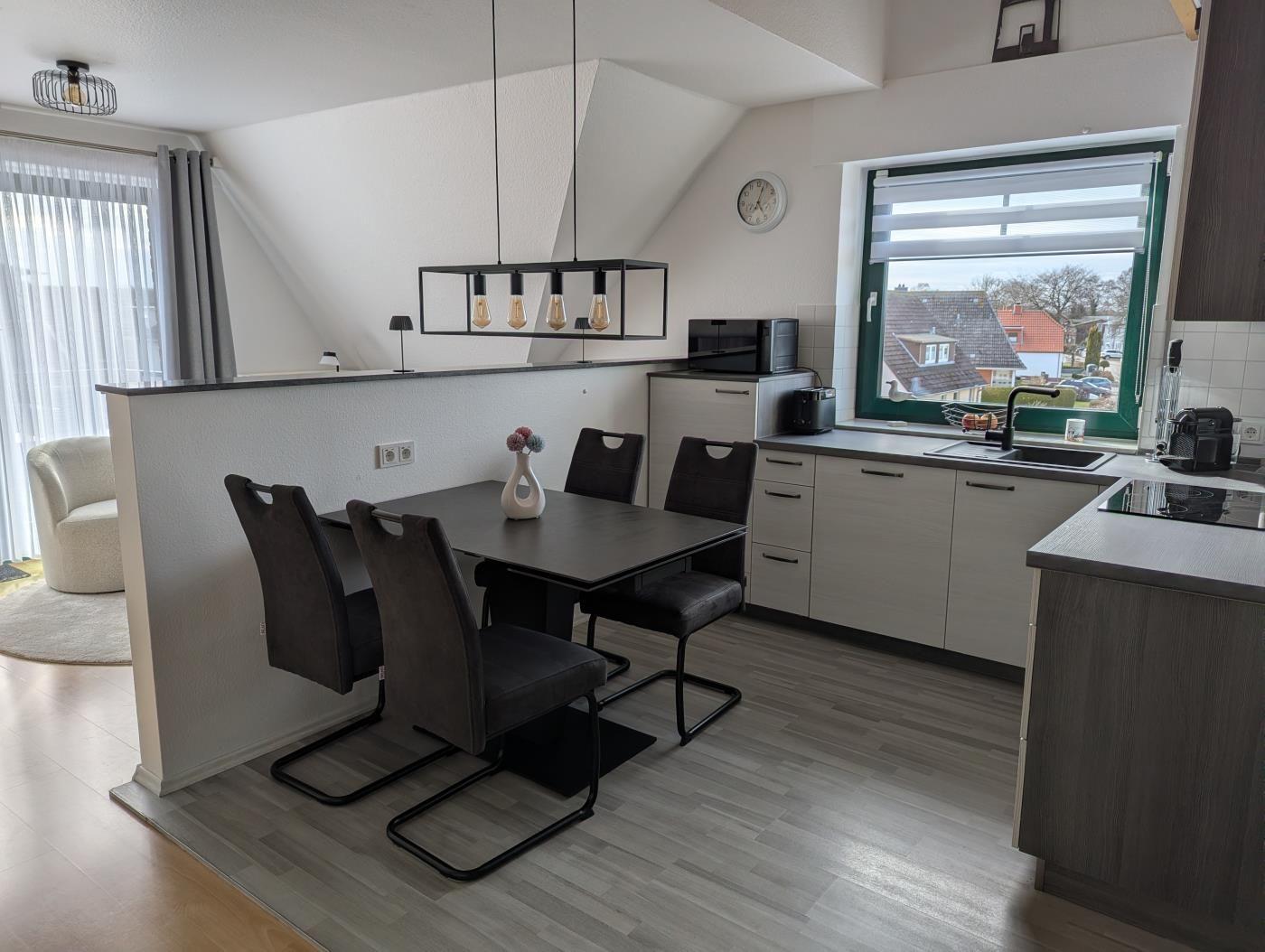 Essbereich mit Tisch und Stühlen, Küche mit Fenster und Küchenzeile.