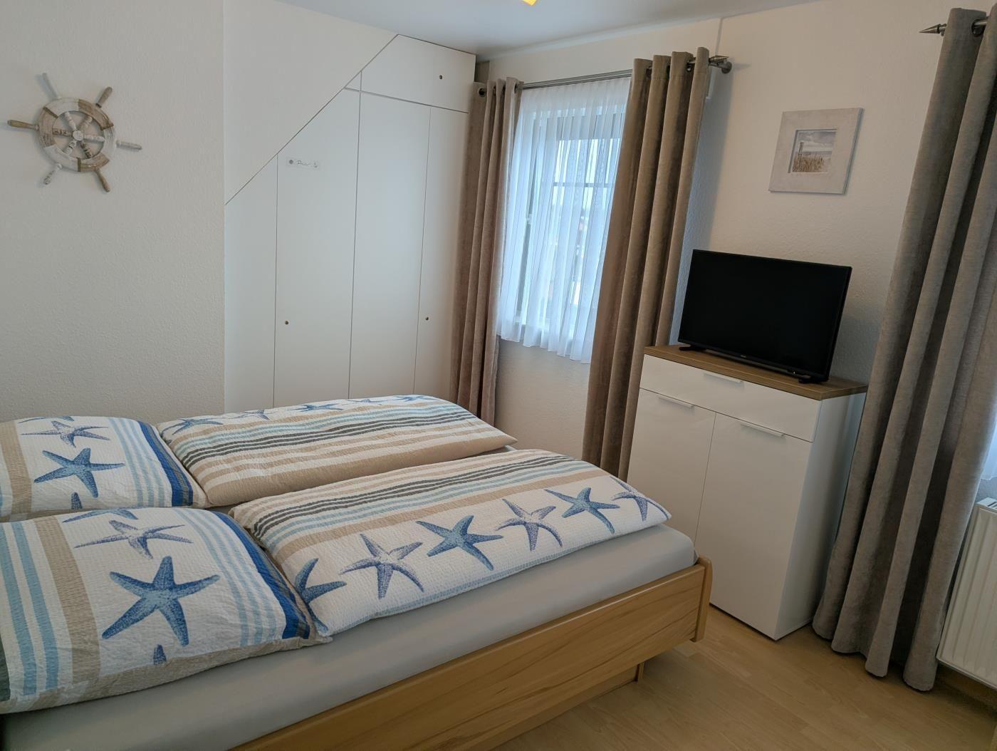 Schlafzimmer mit Bett, TV und Gardinen