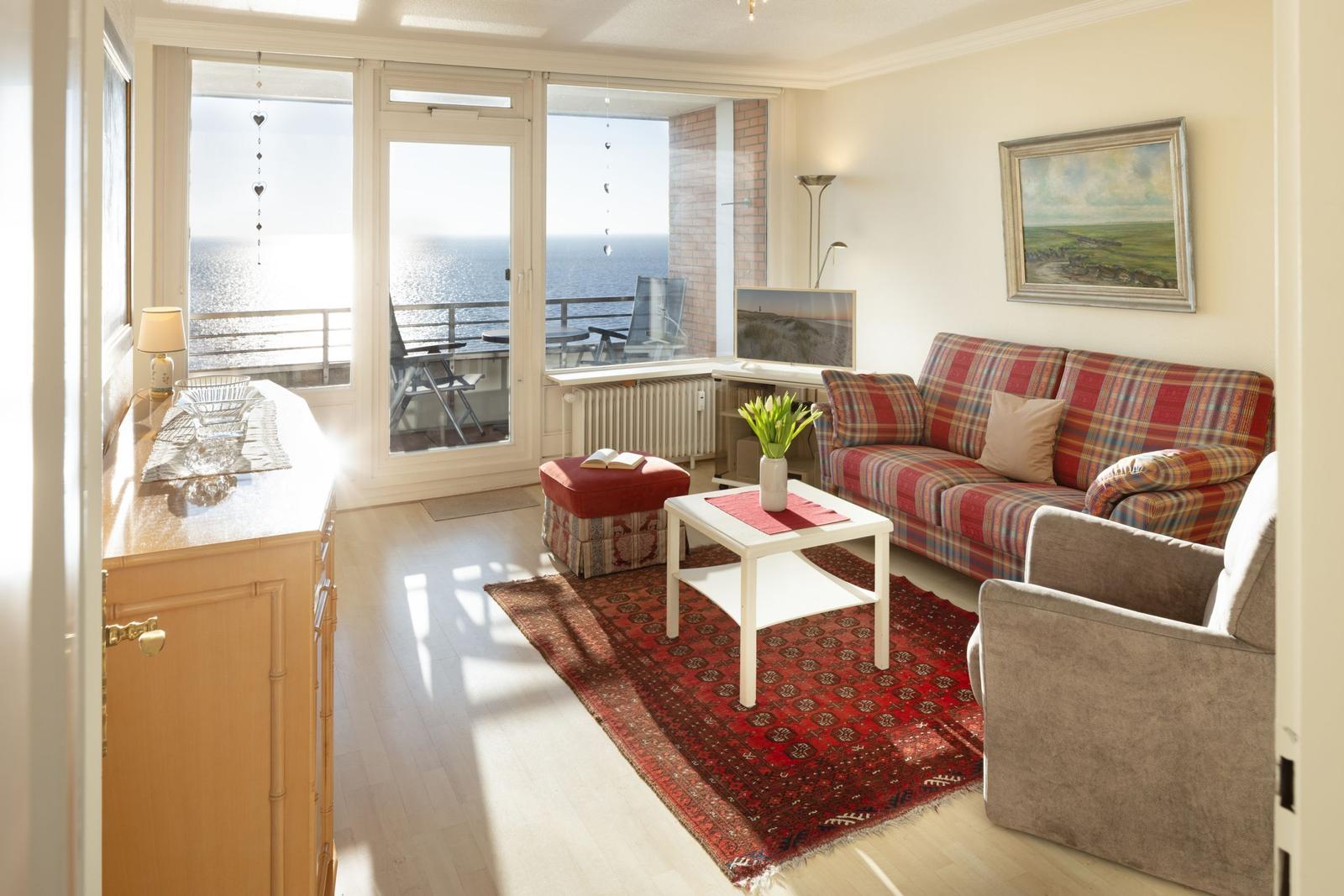 Wohnzimmer mit Blick aufs Meer, Sofa, Couchtisch und Teppich.