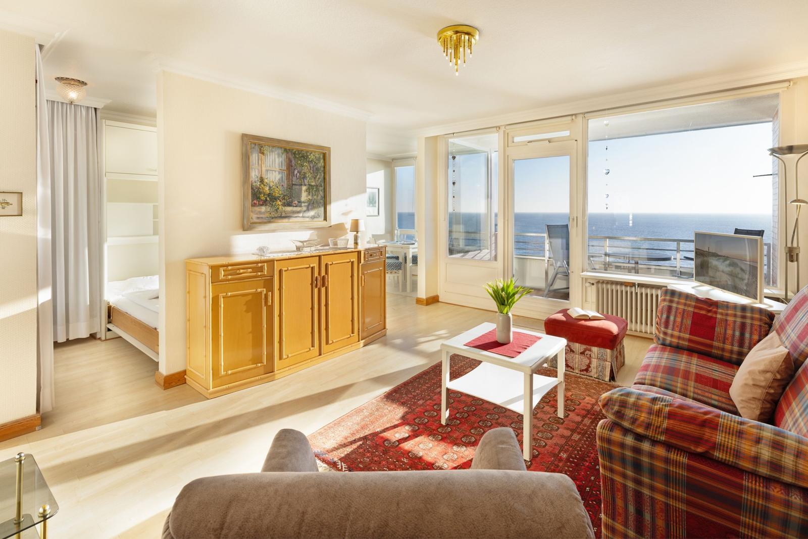 Wohnbereich mit Sofa, Couchtisch und Blick auf das Meer.