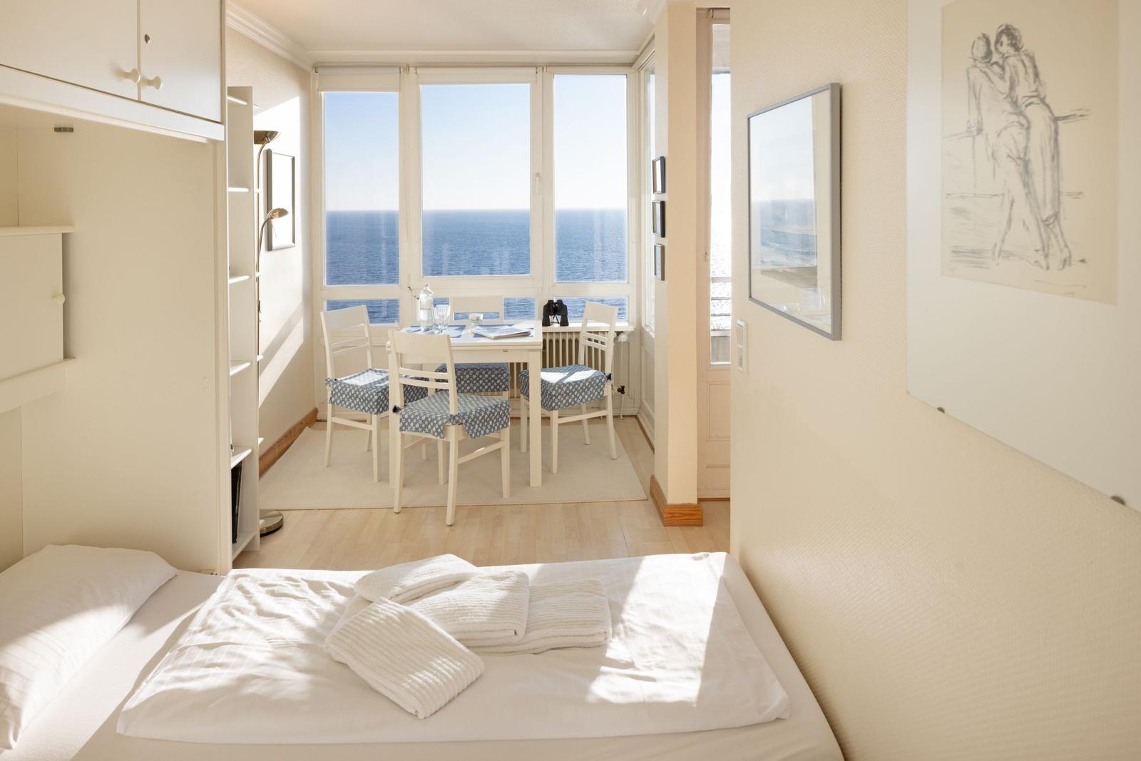 Schlafzimmer mit Blick auf das Meer, Esstisch mit Stühlen und Wandbilder.
