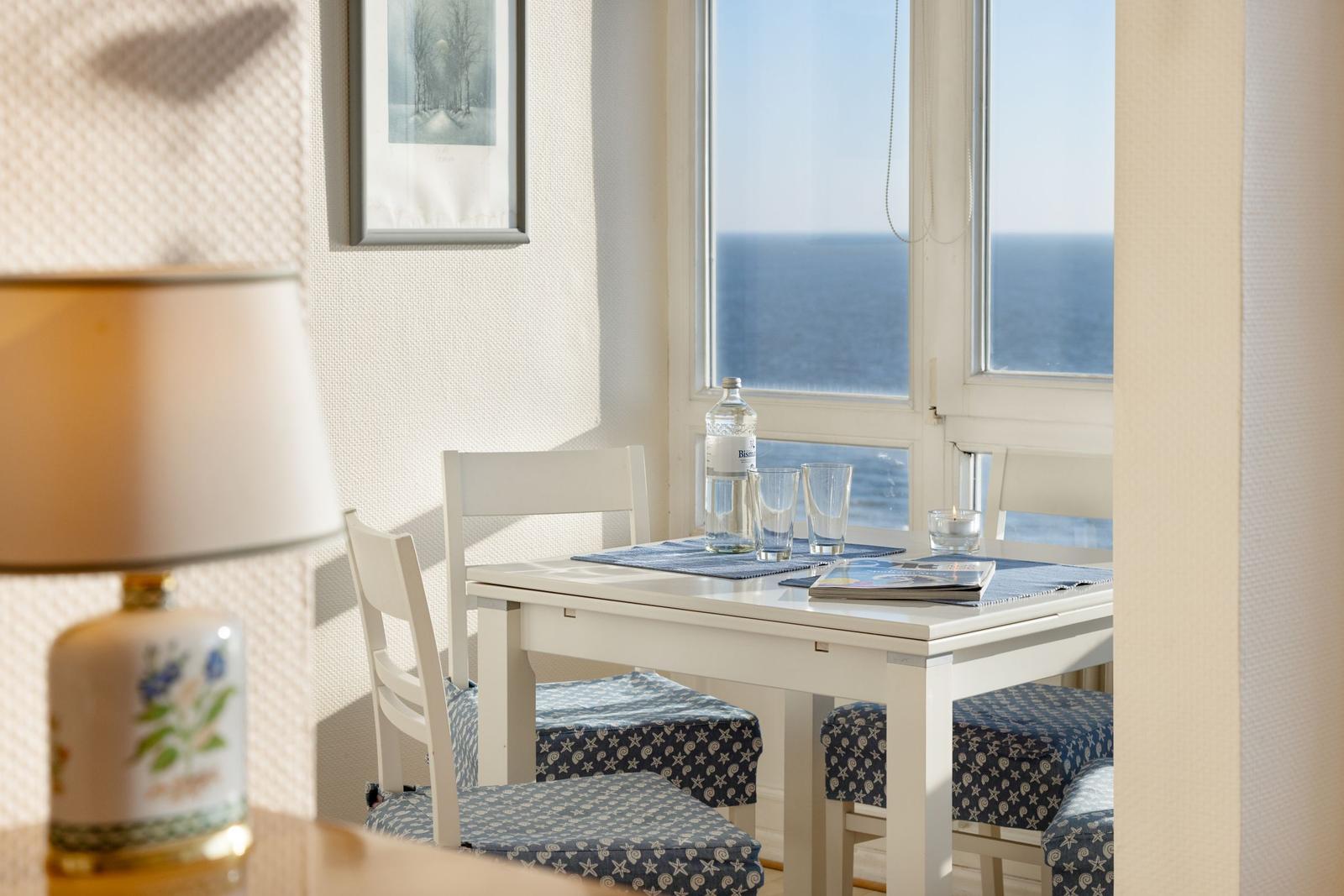 Esstisch mit Stühlen und Blick auf das Meer.