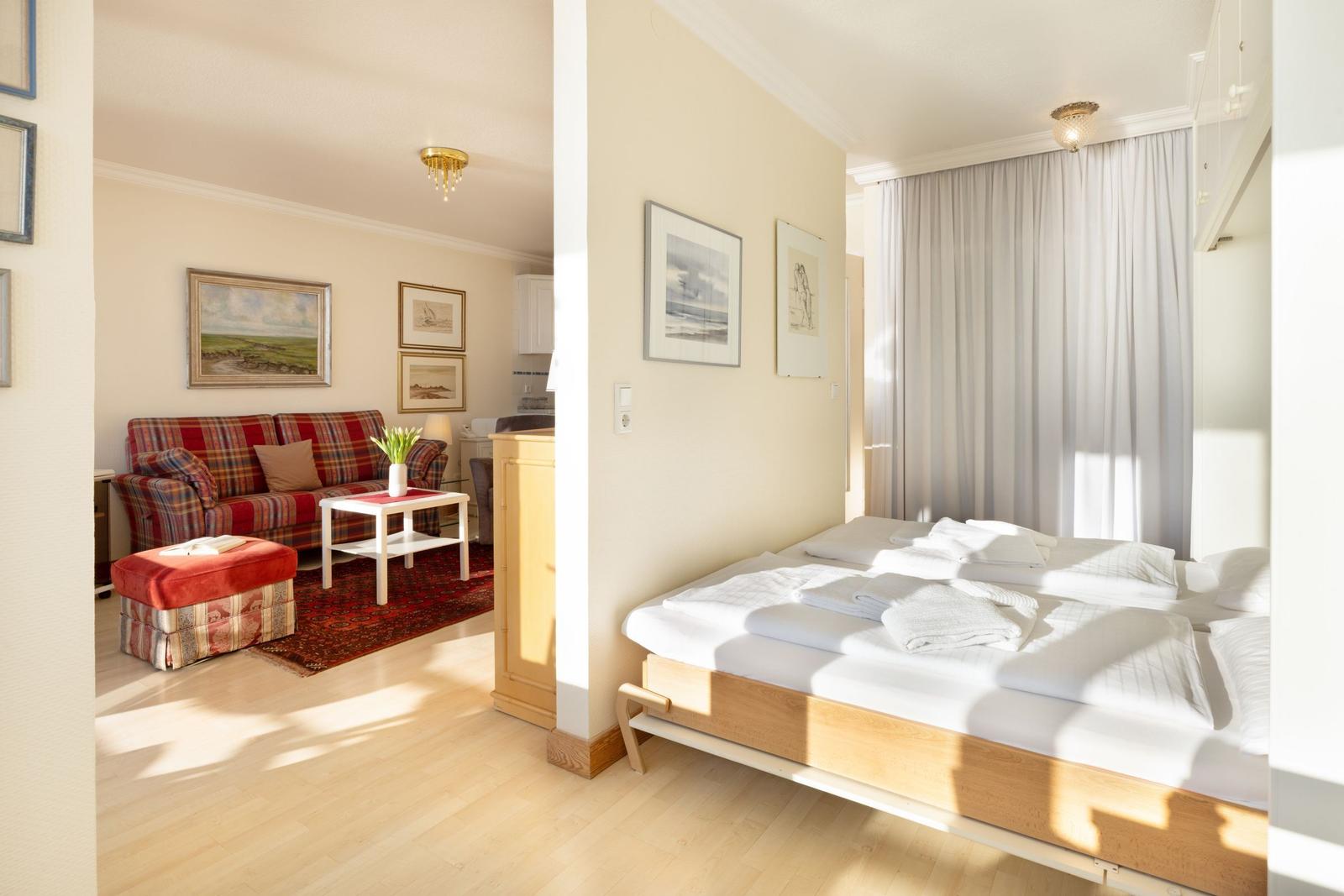Schlafzimmer mit Bett und Wohnbereich mit Sofa und Teppich.