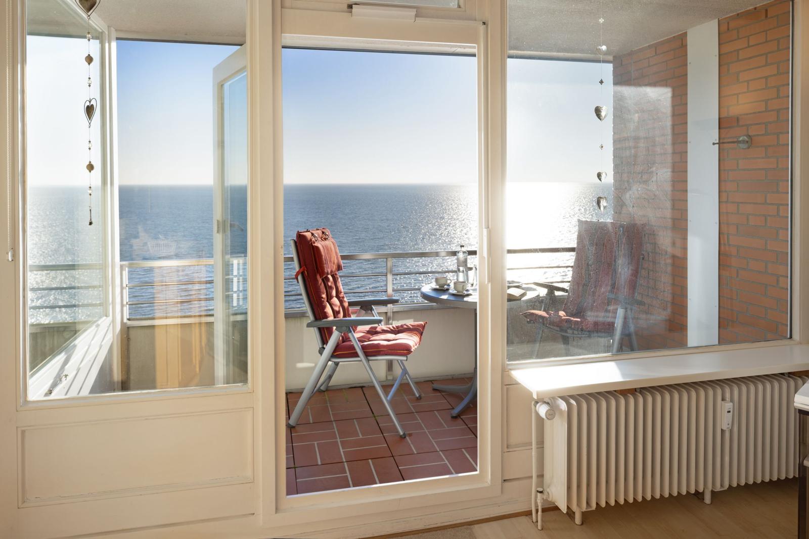 Terrasse mit Blick auf das Meer, rote Sitzgelegenheit und Tisch.
