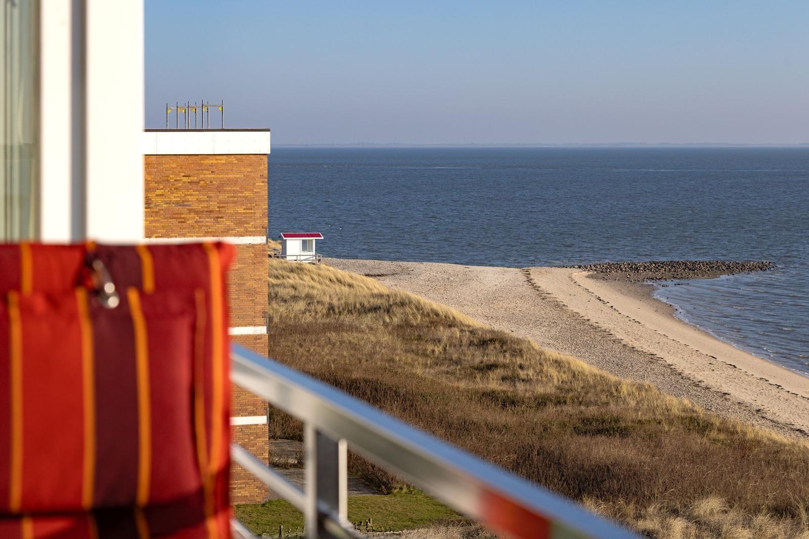 Blick von Balkon auf Strand und Meer mit kleinem weißen Haus