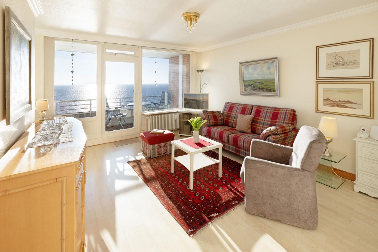 Wohnzimmer mit Sofa, Sessel und Blick aufs Meer.
