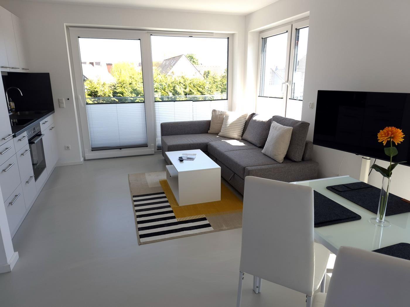 Wohnung mit Küche, Wohnzimmer und Essbereich. Große Fenster und Balkon.