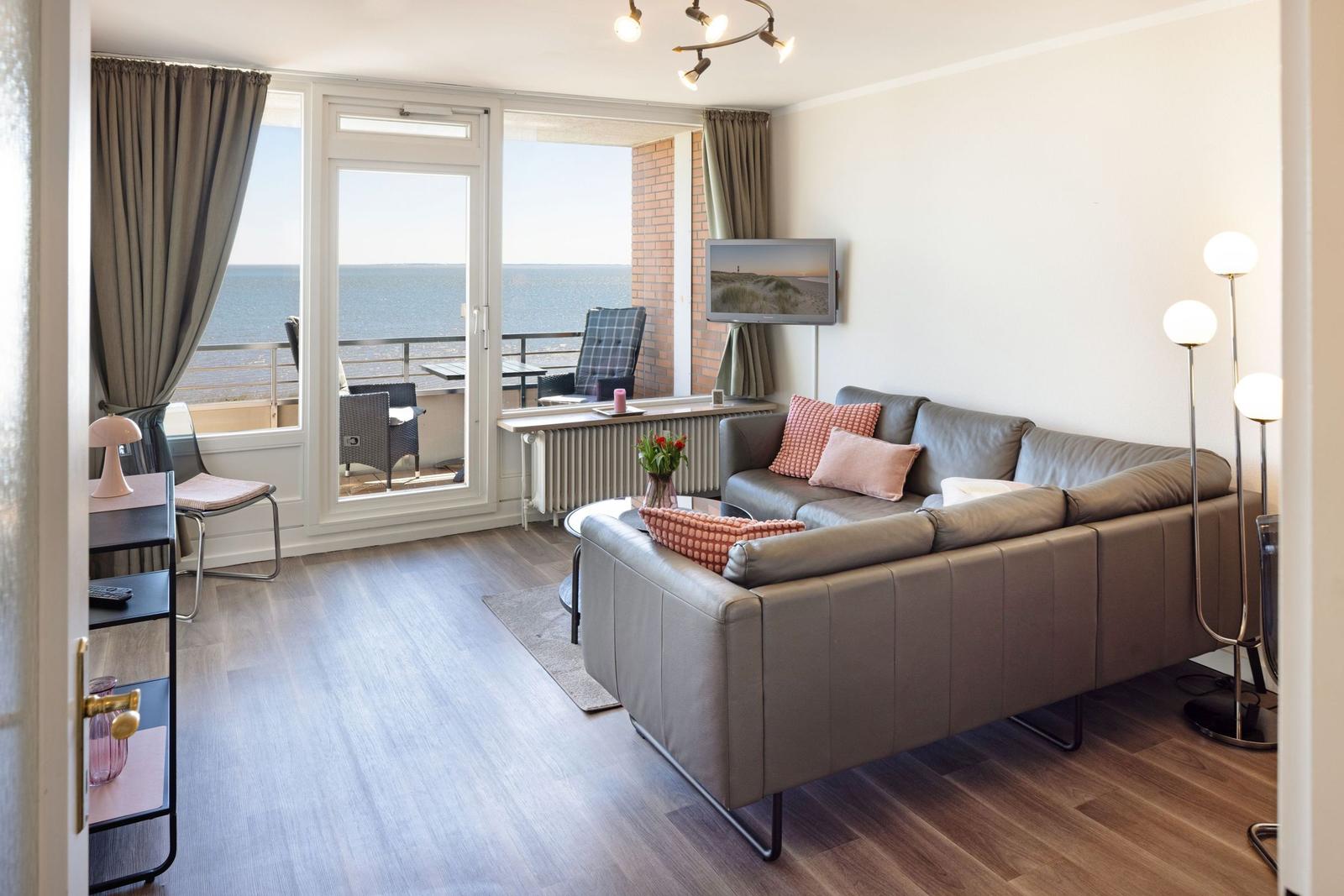Wohnzimmer mit Sofa, Fernseher und Balkon mit Meerblick.