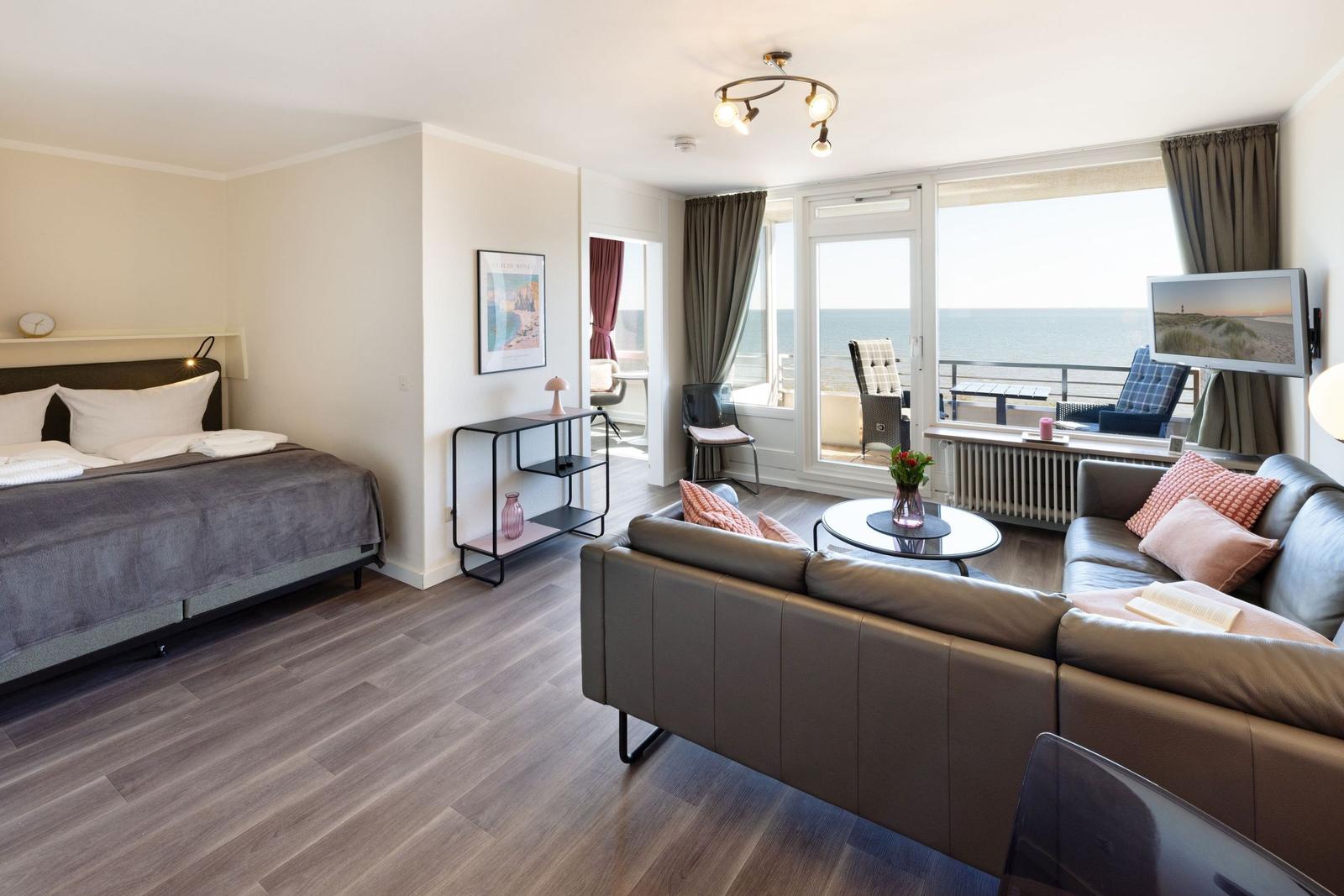 Ein Wohnzimmer mit Sofa, Bett und Balkon mit Meerblick.
