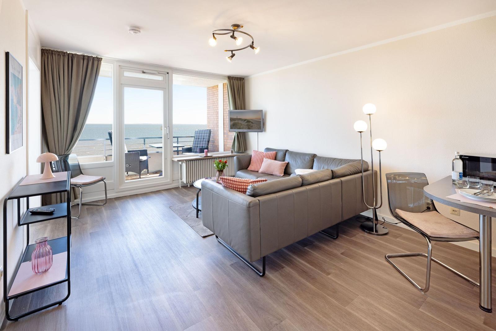 Wohnzimmer mit Sofa, Esstisch und Balkon mit Meerblick.