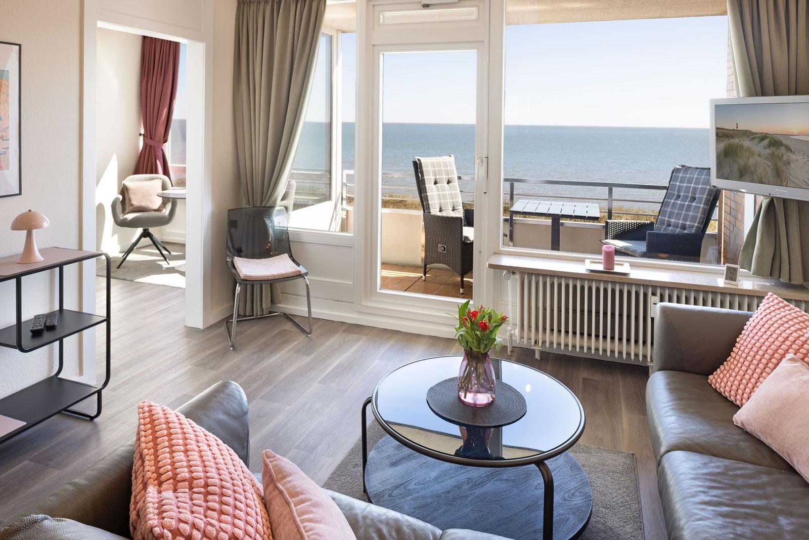 Wohnzimmer mit Meerblick, Sofa, Tisch und Balkonmöbel.
