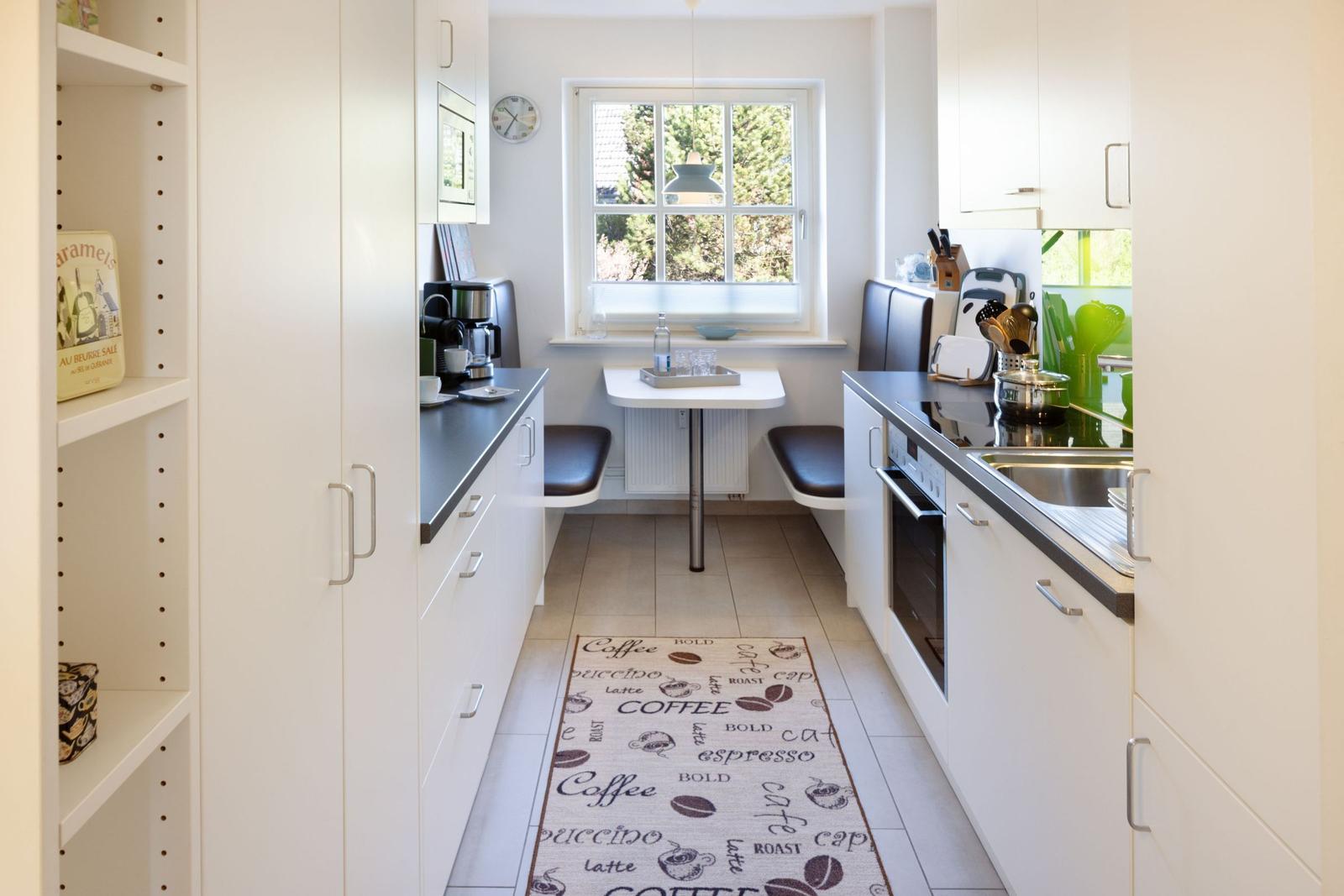 Kitchen with dining area, window, and coffee-themed rug.