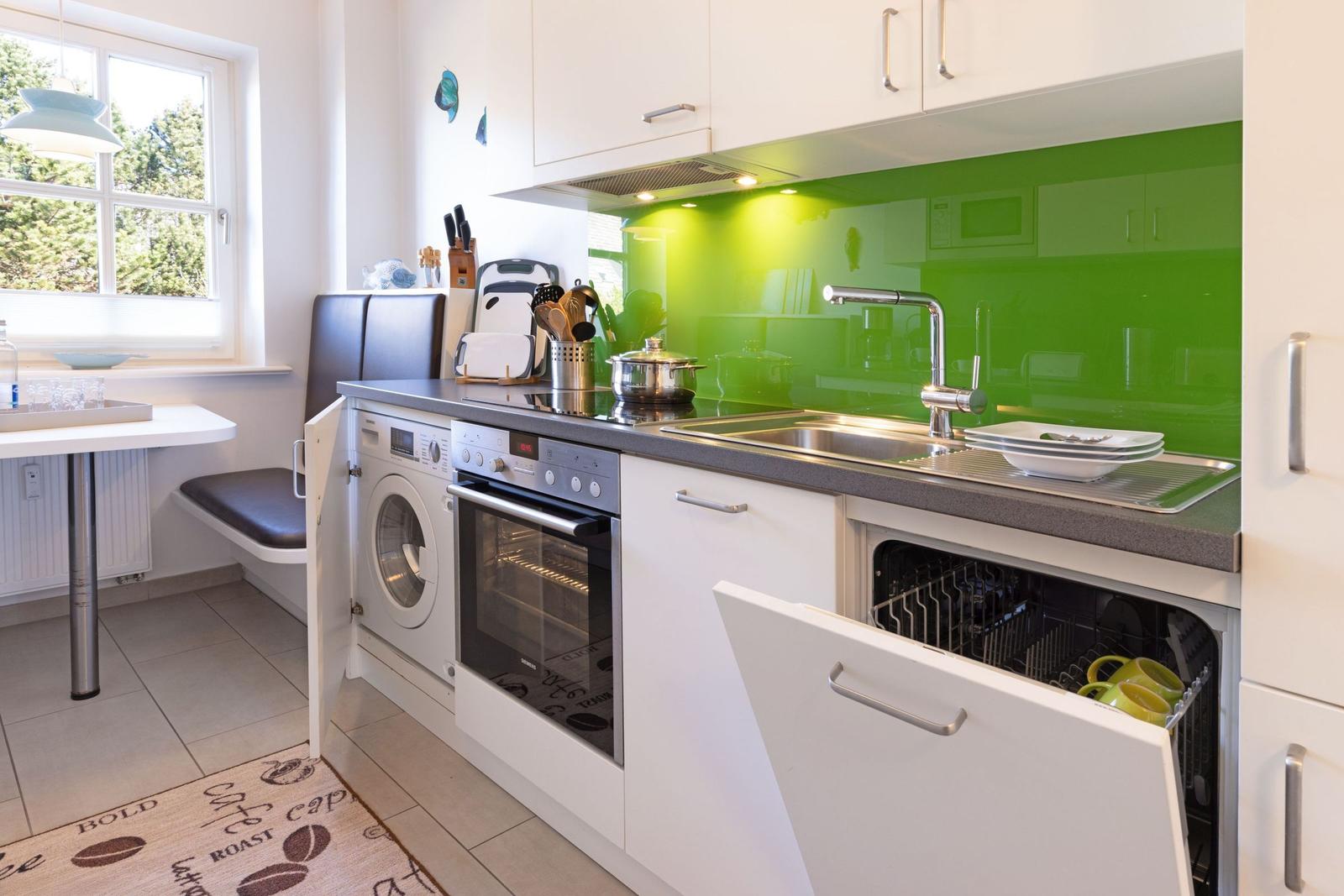 Kitchen with green backsplash, sink, stove, oven, and dishwasher.