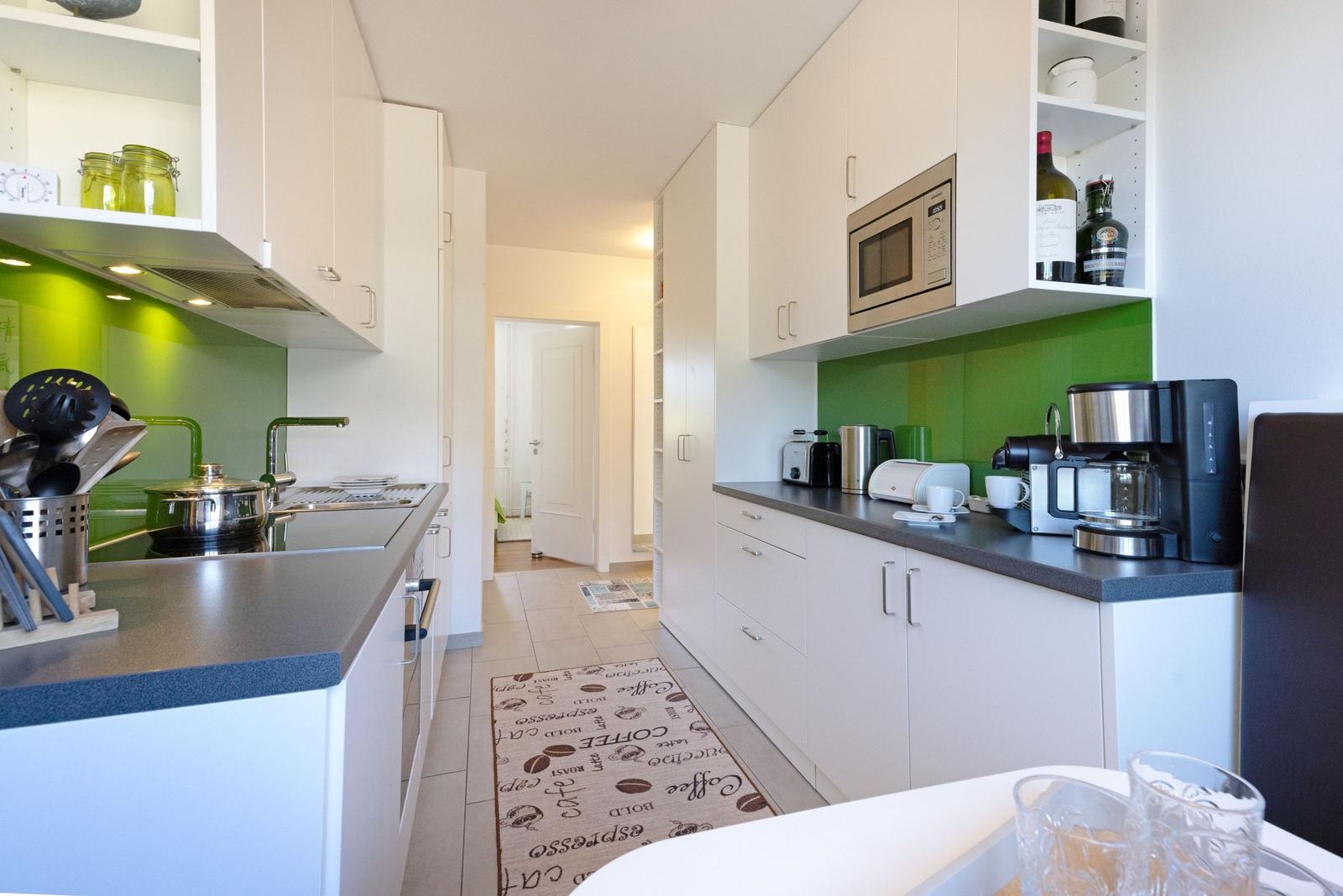 Modern kitchen with white cabinets, green backsplash, and kitchen counter.