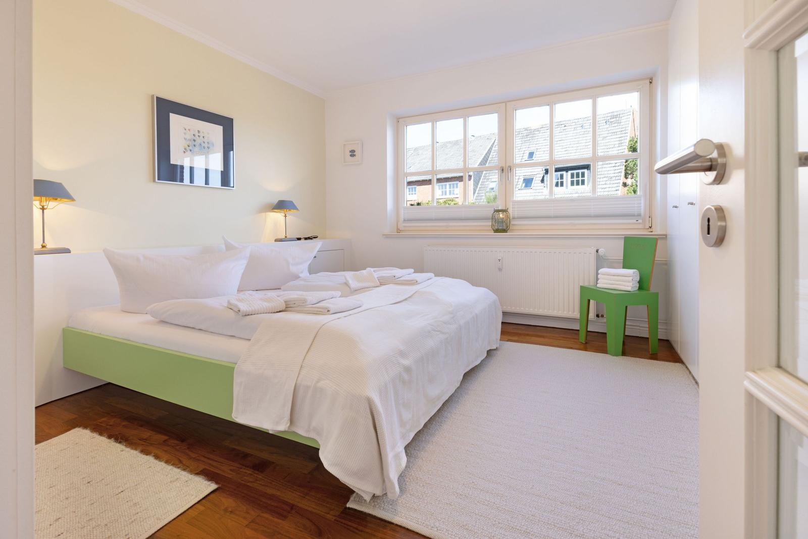 Bedroom with bed, window, and green chair corner.