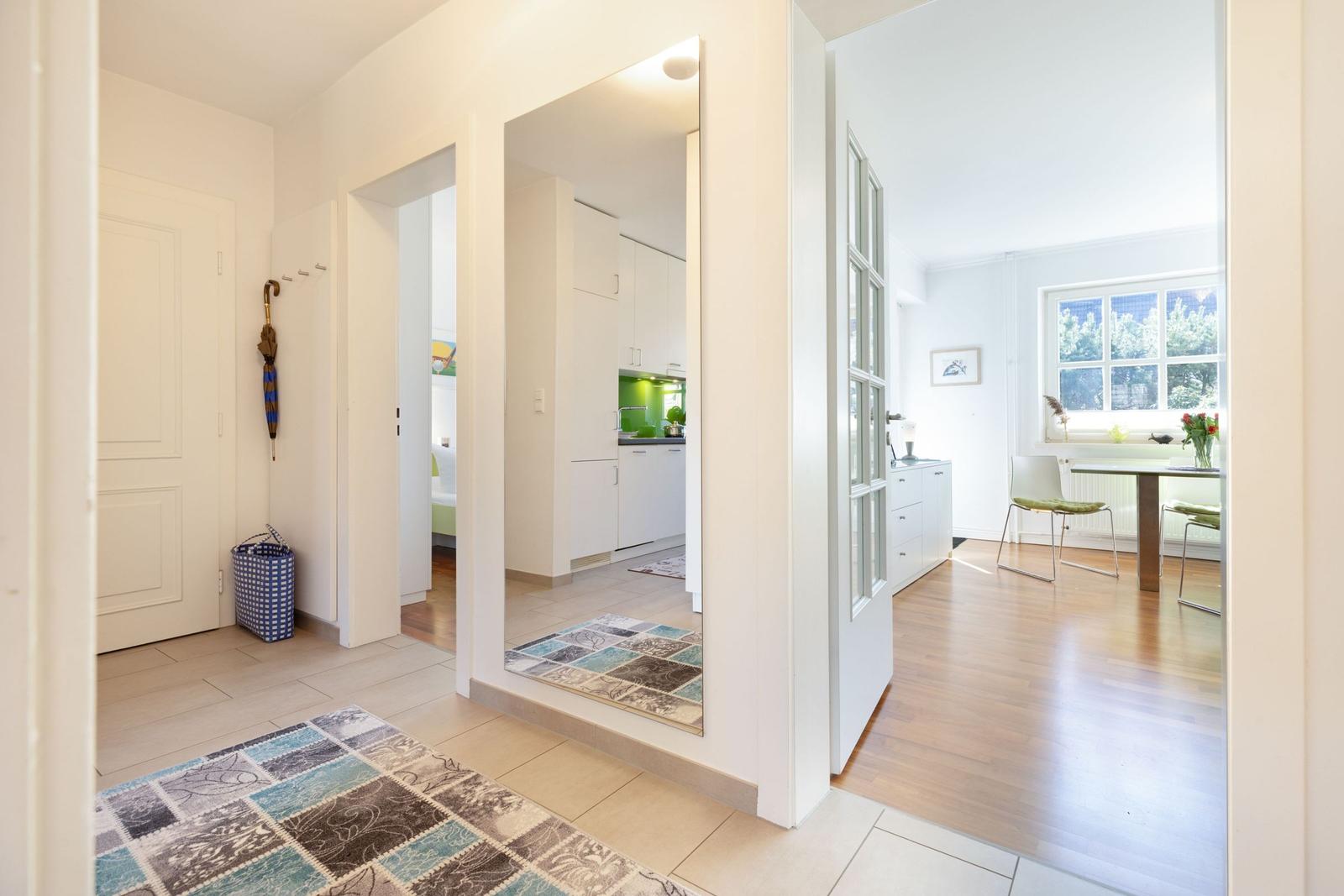 Entrance area with view into kitchen and dining room with wooden floor and window.