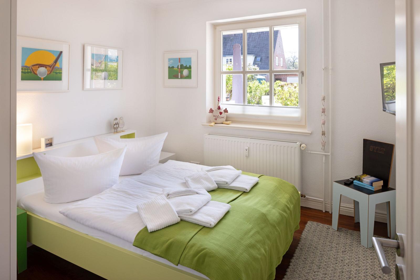 Bedroom with bed, window, and wall pictures