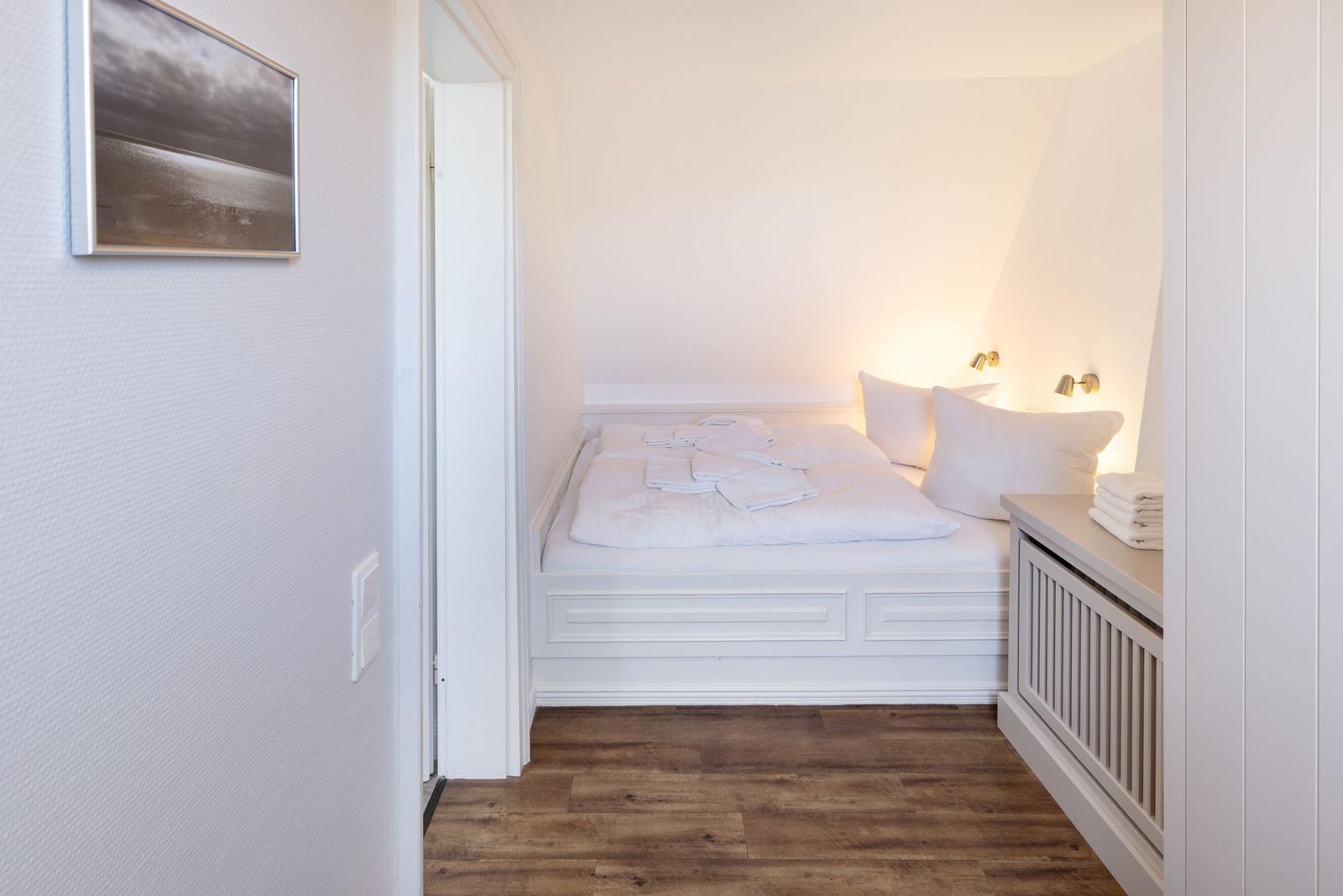 Schlafzimmer mit weißem Bett, Holzboden und Wandbild