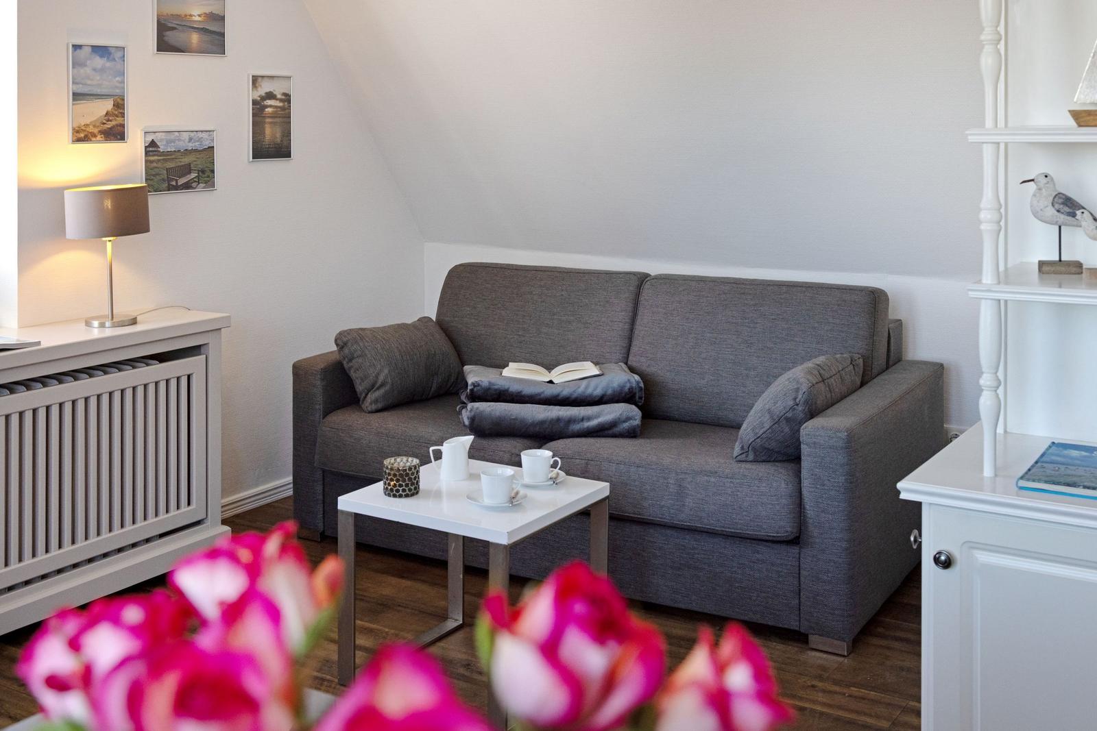 Ein Wohnbereich mit grauem Sofa, weißem Couchtisch und Wandbildern.