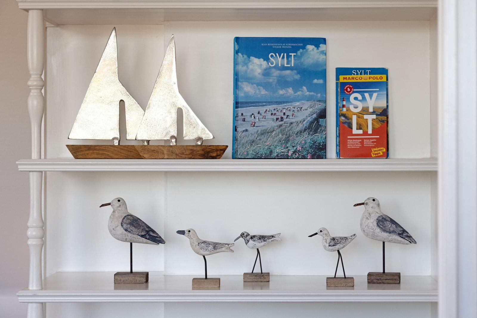 Regal mit Segelboot-Modell und Büchern über Sylt sowie Vogeldekoration.