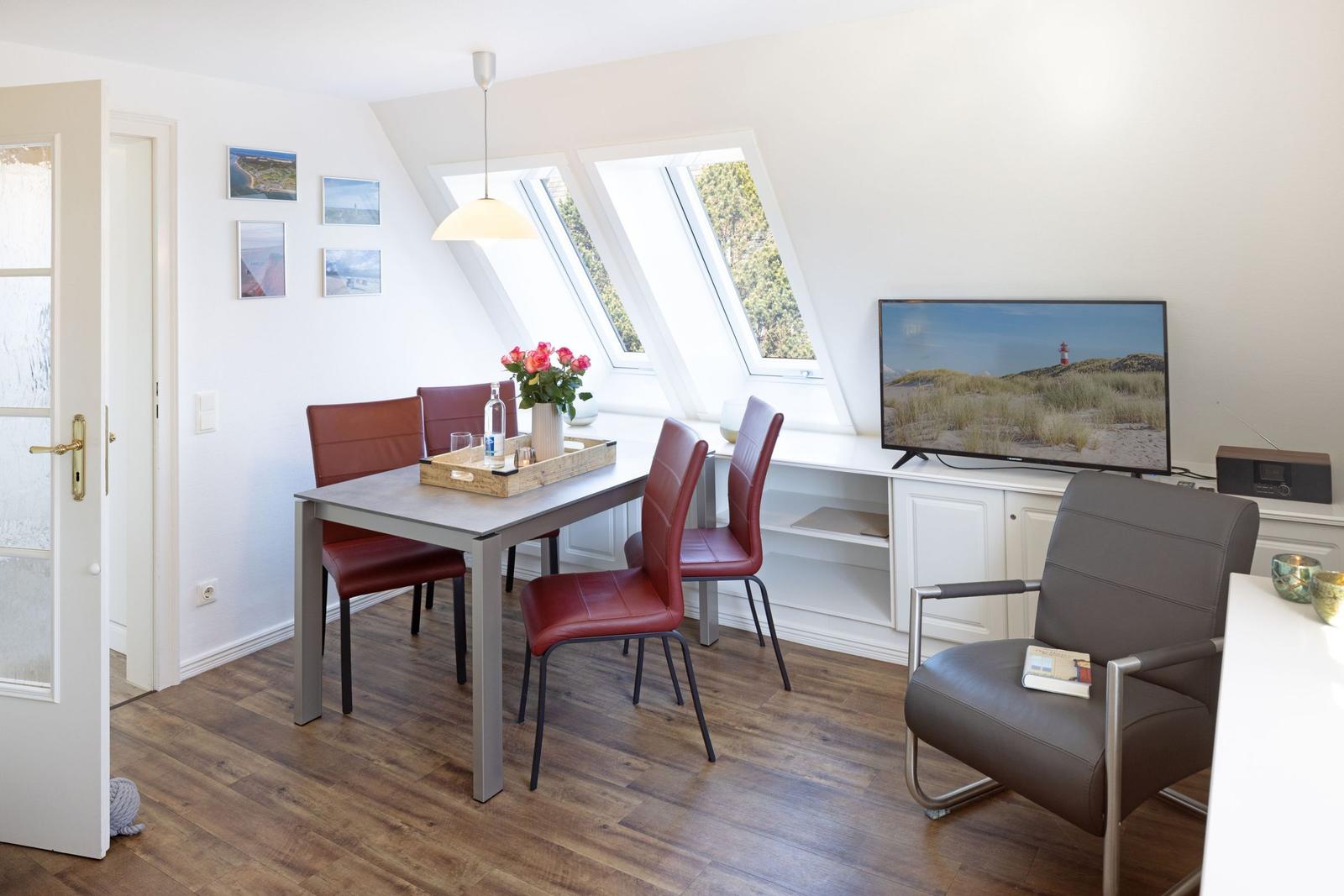 Ein Essbereich mit roten Stühlen und einem Fernseher an der Wand.