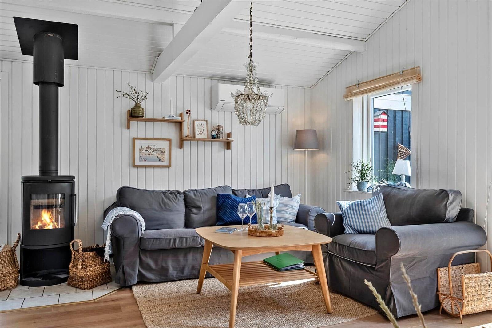 Wohnzimmer mit Sofa, Kamin und Holztisch. Weiße Wände und Holzboden.