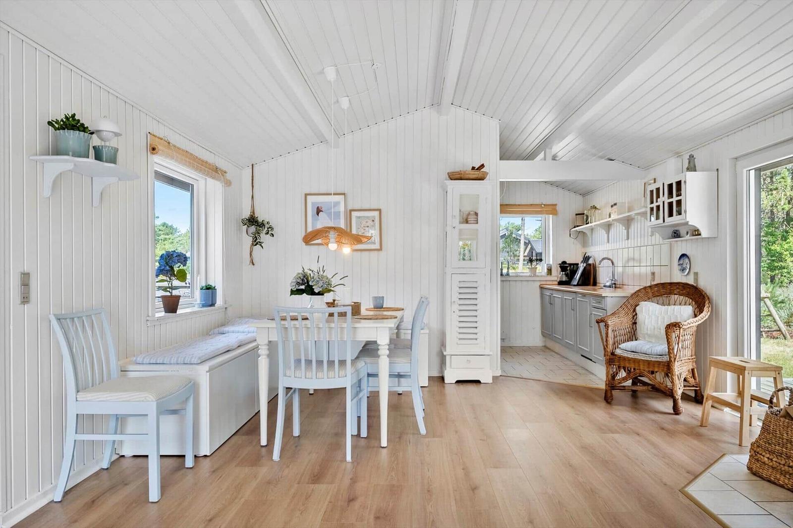 Esszimmer mit Tisch, Stühlen und Fenster. Küche mit Arbeitsplatte und Sitzgelegenheit.