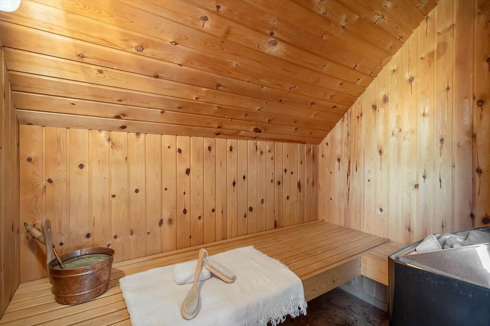 Holzsauna mit Bank, Körbchen und Bürsten. Dampfheizung und Badewanne sind vorhanden.