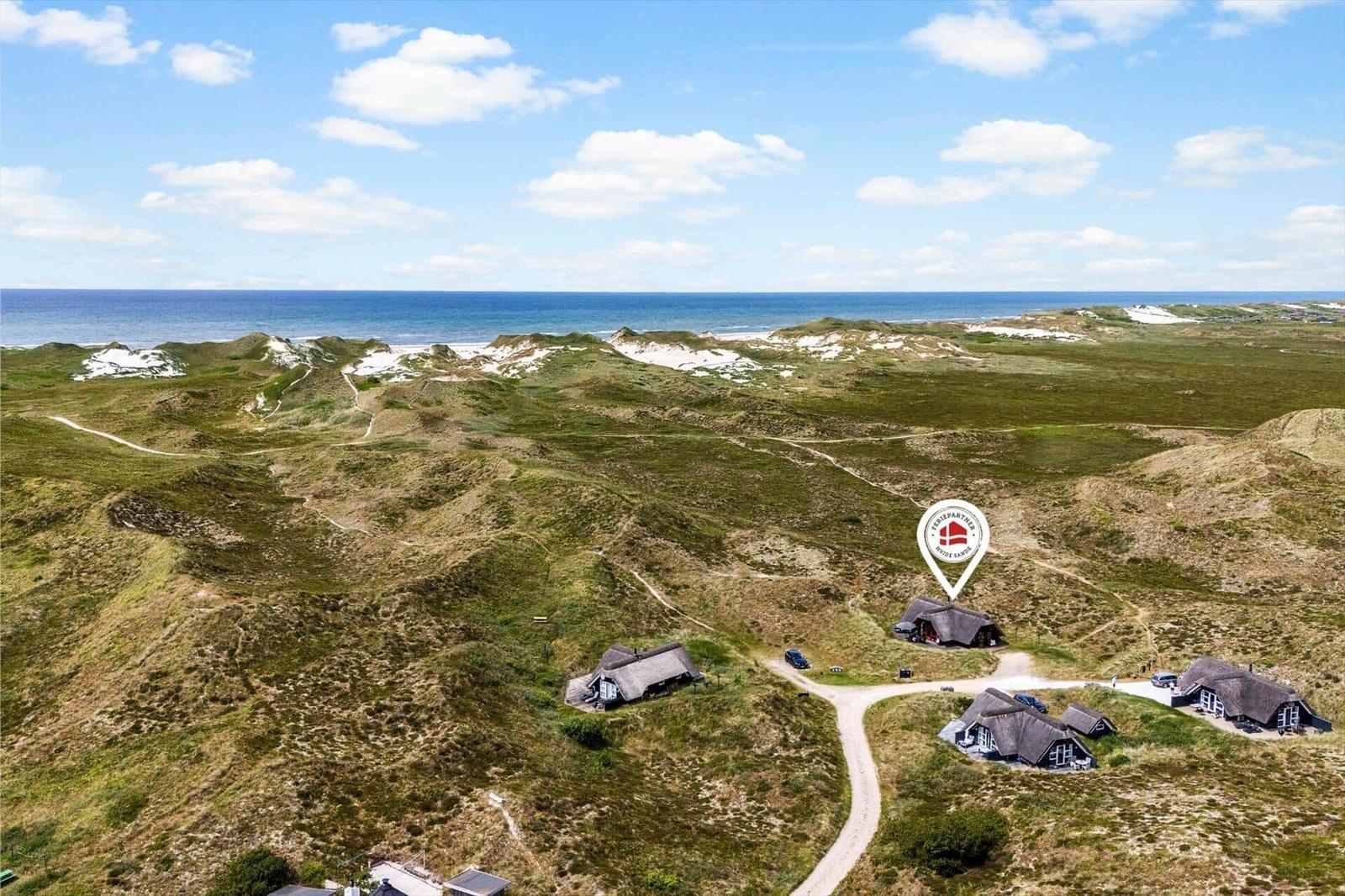 Hütten auf grünen Dünen mit Blick auf das Meer.