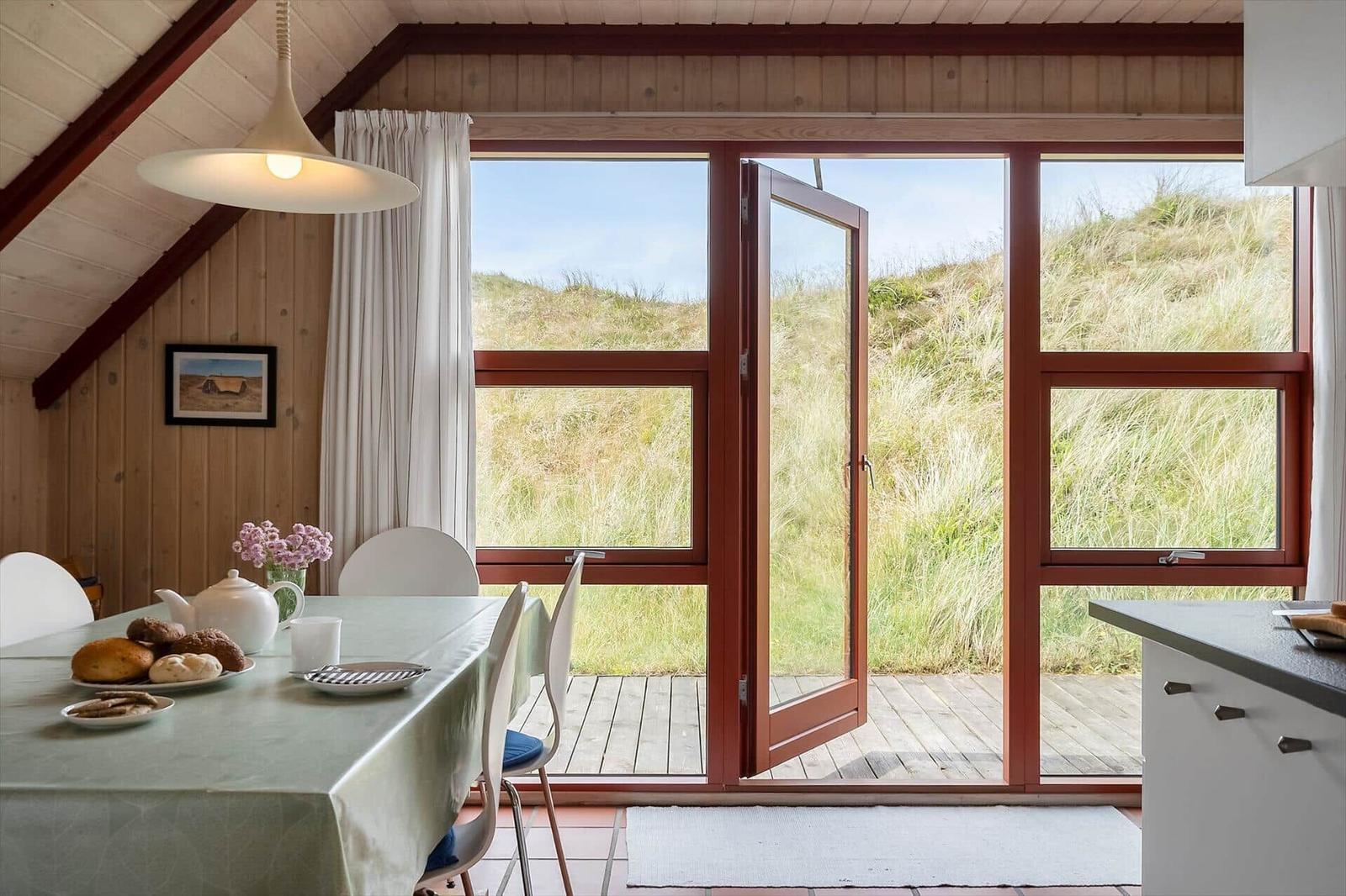 Esszimmer mit Blick auf Graslandschaft durch große Fenster.