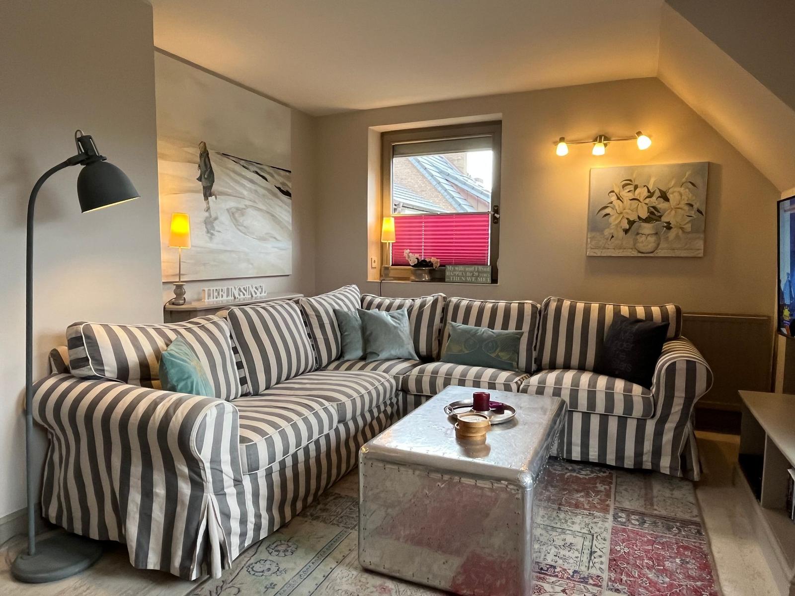Living room with striped sofa, coffee table, and wall art.