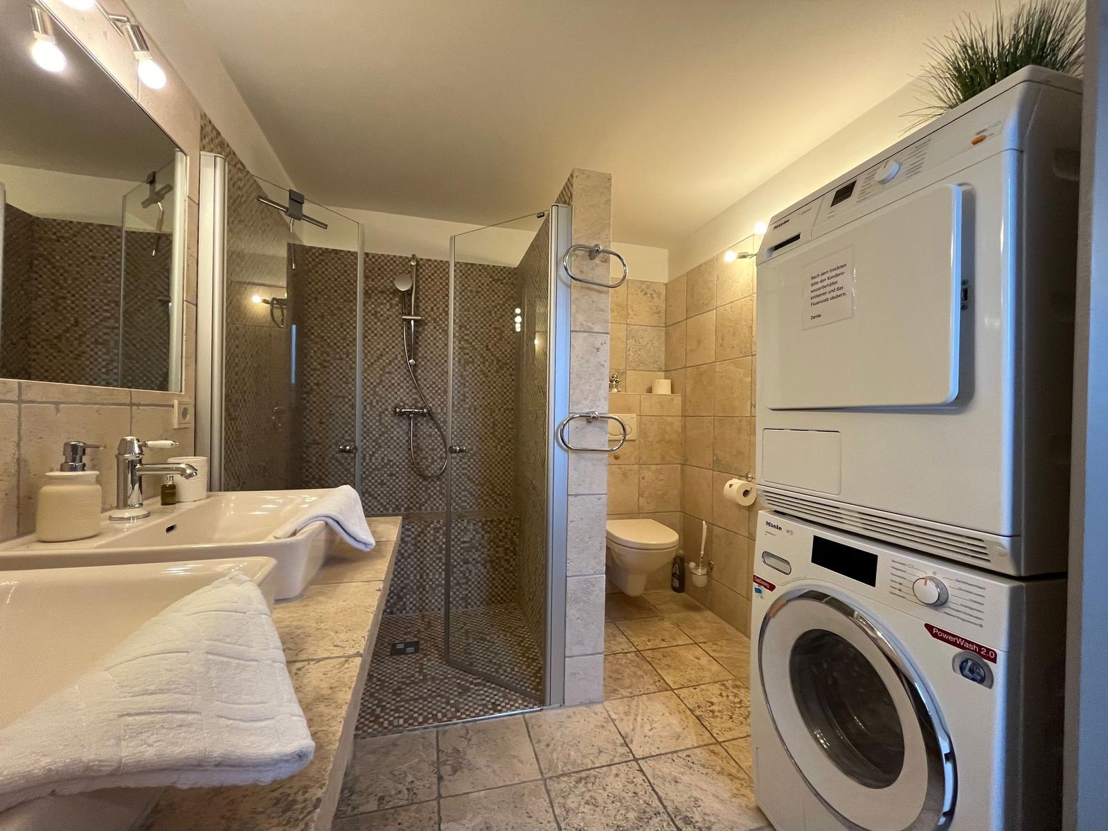 Bathroom with shower, washing machine, and dryer
