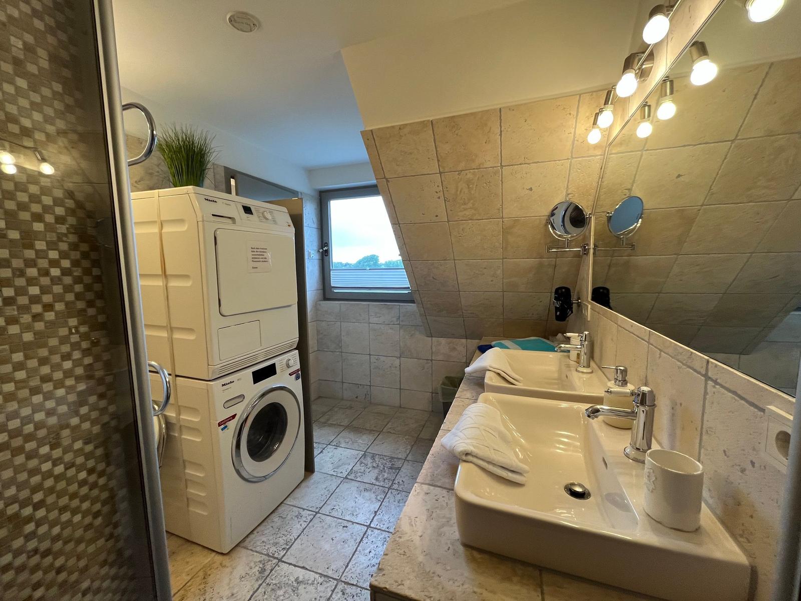 Bathroom with washing machine, mirrors, and window