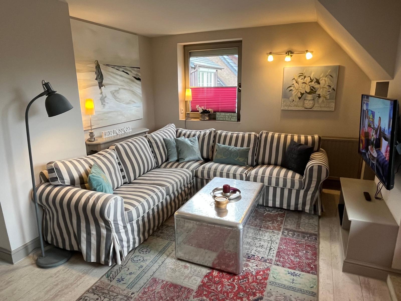 Living room with striped sofa, coffee table, and TV.