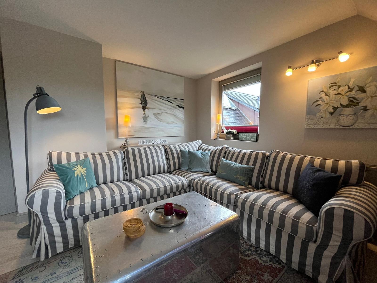 Living room with striped sofa, metal table, and wall art.