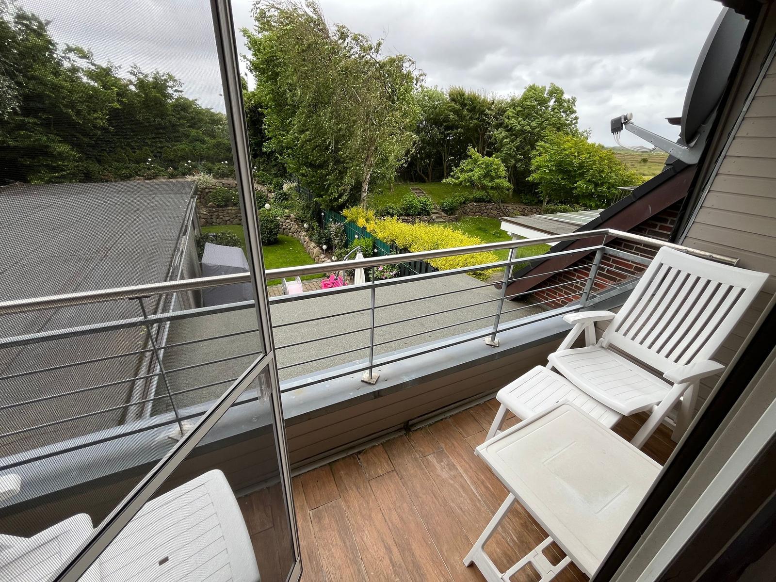Terrace with white chairs and view of green garden